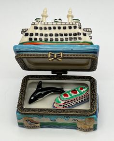 a small box with a boat and a dolphin on it's lid, sitting in front of a white background