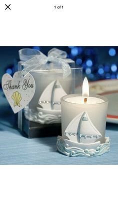 a white candle with a sailboat on it and a thank you card next to it