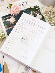 an open book sitting on top of a table next to scissors and flowers with writing in it