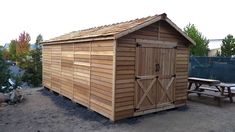 a wooden shed sitting next to a picnic table