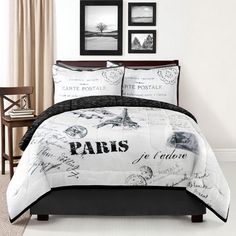 a bed with black and white comforter in a room next to pictures on the wall