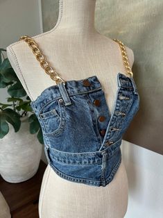 a mannequin wearing a denim top with gold chains on the front and back