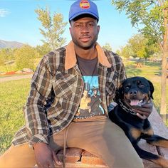 a man sitting on top of a wooden bench next to a black and brown dog