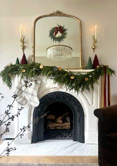 a fireplace decorated for christmas with greenery and stockings on it's mantel