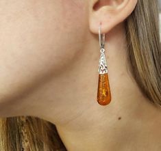 A beautifully crafted unique Baltic Amber pair of earrings. Featuring large teardrop shaped cognac Amber gemstones with a detailed sterling silver frame.Material: Authentic Baltic Amber and 925 sterling silverDimensions: 56 x 10 mm ( 2.20 x 0.39 in )Color: CognacFastening: Lever backFinish: PolishedThe Amber gemstones are a deep and classic cognac hue which shines brightly in natural light. The Amber teardrops are full of natural intricate flakes. The gorgeous open sterling silver work feature o Brown Teardrop Earrings For Formal Occasions, Orange Teardrop Earrings For Formal Occasions, Formal Brown Teardrop Earrings, Formal Orange Teardrop Earrings, Hypoallergenic Amber Teardrop Earrings, Amber Teardrop Earrings, Elegant Brown Pierced Teardrop Earrings, Elegant Brown Teardrop Earrings For Gift, Elegant Brown Teardrop Pierced Earrings