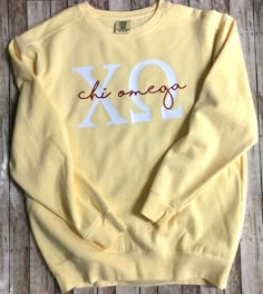 a yellow sweatshirt with the word xo on it sitting on top of a wooden floor