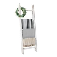 an old white ladder with a wreath on top and towels hanging from it's sides