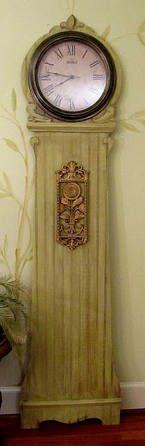 a grandfather clock sitting on top of a wooden floor next to a plant and potted plant