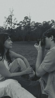 two people sitting on the ground and one is holding a camera