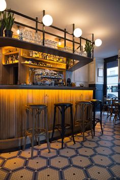 a dimly lit bar with stools in front of it and lights on the ceiling