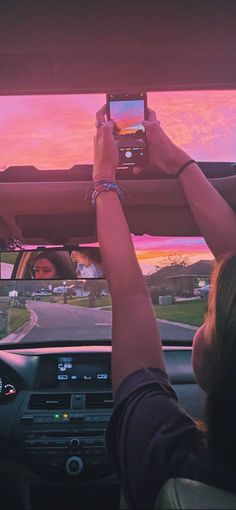 two people are taking pictures in the back seat of a car with their cell phones