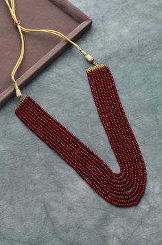 a long red beaded necklace sitting on top of a gray table next to a tray