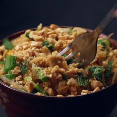 a bowl filled with rice and veggies being spooned into the side dish