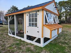 a chicken coop in the middle of a grassy area with a blue roof and windows