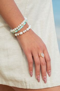 "Flanked with natural white fresh water pearls pikake shell flowers, this unique bracelet evokes visions of Hawaii's white sands and soothing shores. Stack this gold bracelet with other beaded beauties and you'll be ready for your tropical escape. ✦ DETAILS ✦ ✧ Name: Momilani (moh-mee-LAH-nee) - pearl from heaven. ✧ Adjustable from 6.5\"- 8\". ✧ Hand carved mother of pearl pikake. ✧ Natural Freshwater Pearls. ✧ 14kt Gold Filled accents with lobster clasp. ✧ All Ke Aloha Jewelry pieces come packa Elegant White Bracelets For Vacation, White Pearl Bracelet With Charm For Beach, White Spiritual Jewelry For Vacation, White Oyster Bracelet Jewelry For Vacation, Elegant Beaded Jewelry For Vacation, White Hand-strung Pearl Bracelet For Beach, Hand-strung White Pearl Bracelet For The Beach, Gold Bracelets With Gemstone Beads For Beach, Elegant Hand-strung Beaded Bracelets For Beach