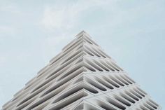 a tall white building with many windows on it's side and the sky in the background