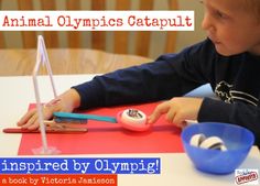 a young boy sitting at a table with an object in front of him that says, animal olympics catapult inspired by olympic