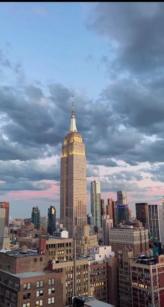 the empire state building towering over new york city at dusk with clouds in the sky