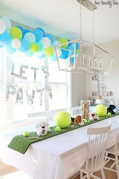 a long table with balloons and stuffed animals on it in the middle of a room