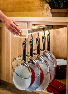 a kitchen cabinet with pots and pans hanging from it's pull out rack