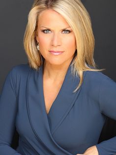 a woman with blonde hair wearing a blue dress and posing for a photo in front of a black background