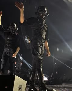 two men in gas masks are performing on stage