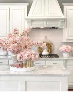 a white kitchen with pink flowers on the counter top and an oven in the background