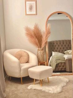 a bedroom with a mirror, chair and ottoman on the floor in front of it