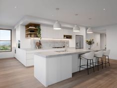 a large kitchen with white cabinets and counter tops, two bar stools next to an island