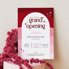 a pink and white cake with red sprinkles on it next to a card that says grand opening