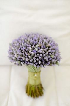 a bouquet of lavenders in a vase on a white sheeted tablecloth, with the stems still attached