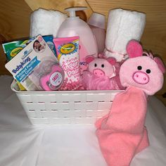 a white basket filled with baby items on top of a bed next to a pink teddy bear