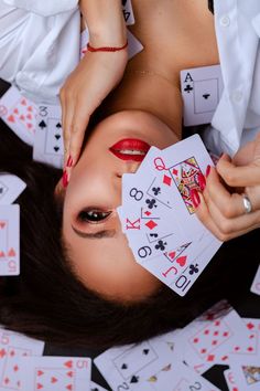 a woman laying on the ground with playing cards in front of her face and hands over her head