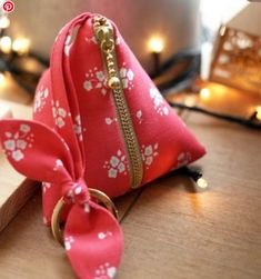 a small red pouch with flowers on it and a gold ring hanging from the front