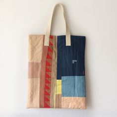 a tote bag hanging on the wall with an orange and blue patchwork design