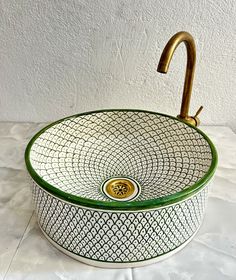 a green and white sink with a brass faucet on the top of it