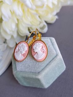 "These cameo earrings are even more beautiful in person.  Classic shell pink and white lady silhouette cameos are set in \"sawtooth-edge\" bezel drop settings. Safely held on the ears with lever back ear wires.  A touch of elegance for any time! Choose your preferred finish from the drop-down menu. Finish options include gold as shown in the main photo, or black. Every effort is made to find opposite facing cameos, but sometimes supply issues exist and both cameos will face the same direction. E Lady Silhouette, Jewelry Book, Small Business Gifts, White Lady, Vintage Portrait, Cameo Earrings, Cardboard Jewelry Boxes, Shell Pink, Vintage Inspired Jewelry