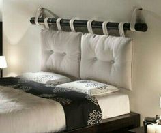 there is a bed with two pillows on the headboard and an iron rail above it