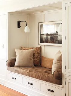 a window seat in the corner of a room with white cabinets and drawers on both sides