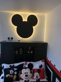 a bed with mickey mouse pillows on it and a light up headboard above the bed