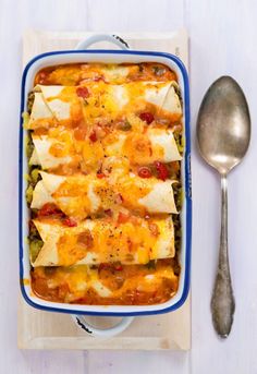 a casserole dish with tortilla shells and cheese on top next to a spoon