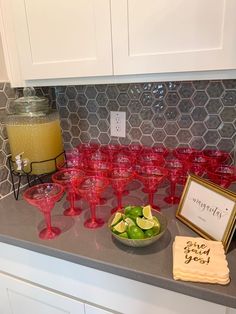 a kitchen counter topped with lots of red wine glasses and limes on top of it