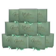 six green envelopes with gold writing on them and bows tied around the top one