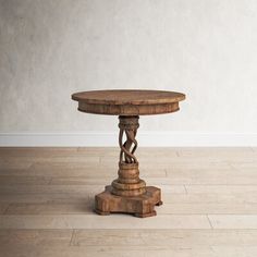 an old wooden table on the floor with a white wall in the backround