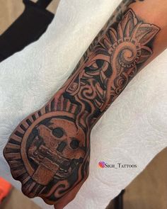 a person with a tattoo on their arm and hand is holding an object in the shape of a skull