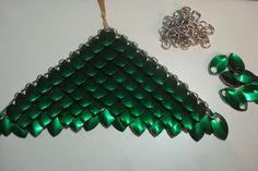 a green christmas tree ornament next to two pairs of scissors and a chain