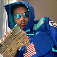 a man in blue jacket and sunglasses holding up stacks of papers with an american flag on it