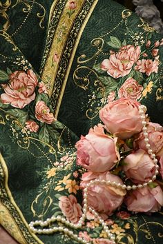 pink roses and pearls are on the green fabric