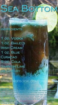 a tall glass filled with blue and green liquid next to a slice of lime on top of