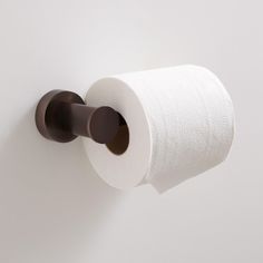 a roll of toilet paper is hanging on the wall next to a brown towel rack